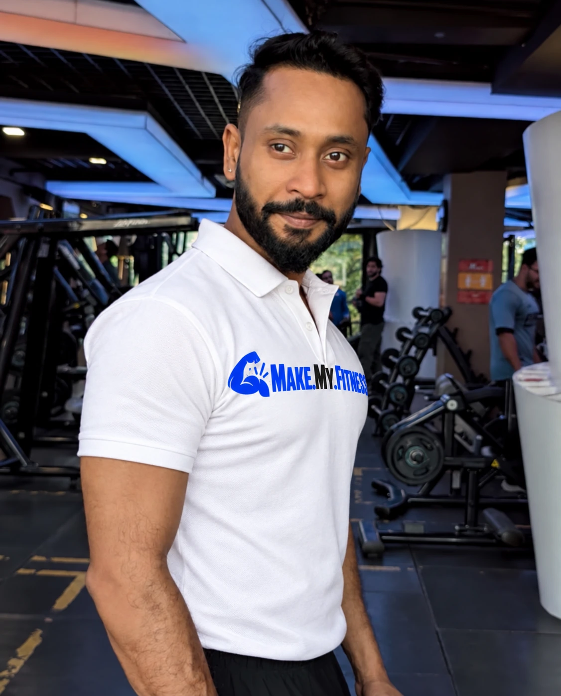 Kumar Abhishek on the gym floor in a white MakeMyFitness polo